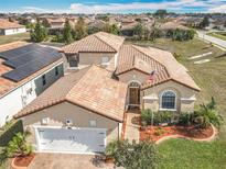 Stunning aerial view of a beige two-story home with a tile roof and a meticulously landscaped front yard at 374 Villa Sorrento Cir, Haines City, FL 33844