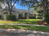 Charming home with a well-manicured lawn, mature trees, and a red front door at 1503 N Greenleaf Ct, Winter Springs, FL 32708
