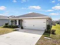 Charming single Gathering home featuring a two car garage, beautiful landscaping and a concrete driveway at 653 Vittorio Dr, Winter Haven, FL 33884