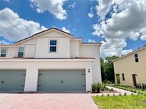 Charming two-story townhome features a brick driveway, two-car garage, and a well-maintained lawn at 571 Bay Leaf Dr, Poinciana, FL 34759
