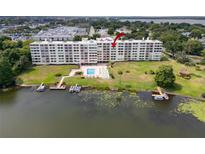 Waterfront condominium with a beautiful pool, boat docks, and lush landscaping with mature trees and green grass at 700 Mirror Nw Ter # 505, Winter Haven, FL 33881