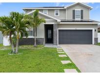 Beautiful two-story home with stone accents, gray siding, and a well-manicured lawn with palm trees at 1741 Hill Top Dr, Dundee, FL 33838