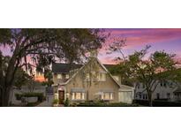Charming two-story home with striped awnings, lush landscaping, and American flag on display at sunset at 140 Cortland Ave, Winter Park, FL 32789