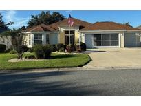 Charming single-story home featuring a well-manicured lawn and a welcoming two-car garage at 348 Ellenton Run, The Villages, FL 32162