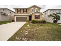 Two-story home with tan siding, red shutters, a brown garage door, and a well-manicured front lawn at 348 Lake Smart Cir, Winter Haven, FL 33881