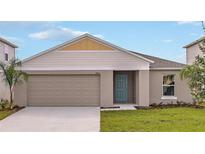 Charming single-story home featuring a light blue front door, beige siding, and a two-car garage at 1010 Foreshore Ln, Haines City, FL 33844
