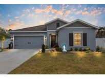Charming single-story home featuring a well-maintained lawn, gray paint, and a two-car garage at 389 Singing Sands Cir, Lake Wales, FL 33859