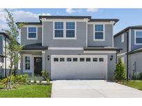 Two-story home featuring a two-car garage, well-manicured lawn, and a classic gray and white color scheme at 284 Woodsage Pl, Lake Alfred, FL 33850