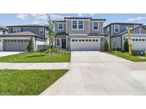 Two-story home with gray siding, lush lawn, and a concrete driveway leading to a two-car garage at 284 Woodsage Pl, Lake Alfred, FL 33850