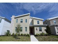 Charming modern home featuring a red front door, stone accents, and landscaped front yard at 2956 Penelope Loop, Kissimmee, FL 34746