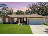 Charming single-story home featuring a well-manicured lawn, attached two-car garage, and classic architectural details at 703 New York Ave, South Daytona, FL 32119