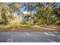 Charming exterior view of a two-story home with a staircase and lush landscaping surrounded by mature trees at 9401 Cat Track Trl, Lake Wales, FL 33898