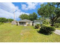 Charming home featuring a screened porch, mature trees, and an oversized detached garage at 14285 Oconner Rd, Kathleen, FL 33849