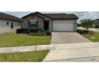 Charming single Gathering home featuring manicured lawn, neutral paint and paver driveway at 168 Claffey Ct, Haines City, FL 33844