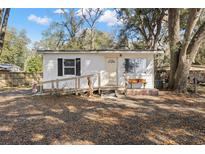 Charming single-story home featuring a front ramp, white siding, and mature trees at 3925 Ne 92Nd Pl, Anthony, FL 32617