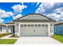 Two-car garage featuring paneled doors and exterior lighting with a concrete driveway, set against a bright, cloudy sky at 3739 Bergamot St, Lake Alfred, FL 33850