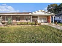 Charming single-story home featuring a screened-in porch, attached garage, and lovely front yard landscaping at 915 E Lake Parker Dr, Lakeland, FL 33801