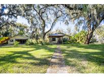 Inviting front yard with mature trees and covered porch, creating a serene and picturesque setting at 9415 Cat Track Trl, Lake Wales, FL 33898