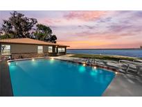 Backyard pool overlooking peaceful water with a beautiful sunset view, and outdoor seating at 830 County Rd 457, Lake Panasoffkee, FL 33538