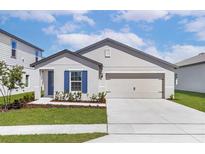 Charming single-story home with a two-car garage, manicured lawn, and bright blue window shutters at 1786 White Elephant Loop, Winter Haven, FL 33884