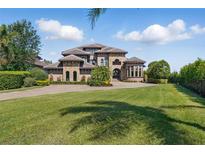 Stunning stone and stucco home with a manicured lawn, lush landscaping, and a paver driveway on a sunny day at 7769 Summerlake Pointe Blvd, Winter Garden, FL 34787
