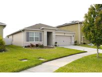 Charming single-story home with neutral paint, gray shutters, well-manicured lawn, and a two-car garage at 1823 Pristine Loop, Lakeland, FL 33811