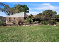 Charming brick home featuring a well-maintained lawn and beautiful landscaping with various plants and trees at 105 Country Club Ln, Mulberry, FL 33860