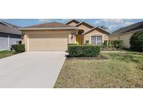 Charming single-story home featuring a two-car garage, manicured lawn, and a welcoming yellow front door at 540 Buckingham Cir, Davenport, FL 33897