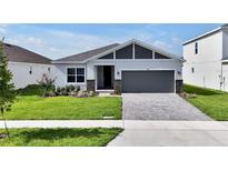Charming single-story home with a well-manicured lawn, gray brick accents, and a spacious driveway at 5774 Greenery Ln, St Cloud, FL 34771