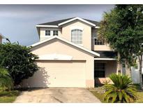 Two-story home with a two car garage, black roof, and well-maintained front yard at 14417 Jasmine Glen Dr, Orlando, FL 32824