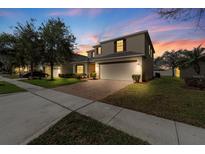 Charming two-story home with a brick paver driveway, manicured lawn, and attached two-car garage at 754 Andalusia Loop, Davenport, FL 33837