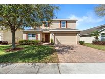 Charming two-story home featuring a well-manicured lawn, brick driveway, and a welcoming two-car garage at 754 Andalusia Loop, Davenport, FL 33837