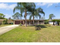 Charming single-story home with a well-manicured lawn, palm trees, and a cozy front porch with rocking chairs at 1062 Mayflower Ave, Deltona, FL 32725