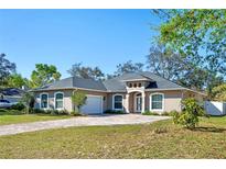 Charming one-story home featuring a paver driveway, manicured lawn, and lush landscaping at 3688 Hurlbut Cir, Lake Wales, FL 33898