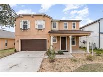 Two-story home with a well-maintained yard, covered entrance, and a two-car garage at 265 Elderberry Dr, Davenport, FL 33897