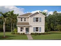 Charming two-story home with light gray and white siding, complemented by a well-manicured lawn and lush landscaping at 5645 Meditation Dr, Clermont, FL 34714