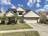 Charming home featuring a two-car garage and a well-manicured front yard with mature landscaping under a beautiful sky at 875 W Charing Cross Cir, Lake Mary, FL 32746
