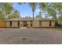 Charming single-story home featuring a central front door, gravel front yard, and mature trees at 31632 Spruce Dr, Eustis, FL 32736
