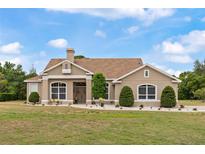 Charming single-story home featuring a landscaped front yard, beige stucco, and a welcoming front entrance at 32421 Wolfs Trl, Sorrento, FL 32776