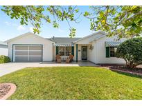 Charming home with well-manicured lawn, awning details, and inviting front seating at 604 Ellsworth Way, The Villages, FL 32162