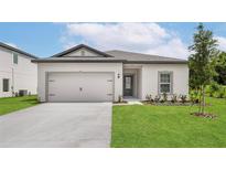 Charming single-story home featuring a well-manicured lawn, neutral color scheme, and a two-car garage at 13276 Tula Loop, Astatula, FL 34705