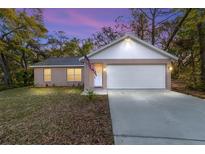Charming single-Gathering home featuring an attached two-car garage and a well-maintained front yard, set beneath a picturesque evening sky at 39832 N Hibiscus Way, Lady Lake, FL 32159