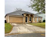 Charming one-story home with tan stucco, two-car garage, and well-maintained lawn and a concrete driveway at 774 Lobelia Dr, Davenport, FL 33837
