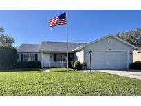 Charming single-story home featuring a well-manicured lawn and a prominent American flag at 620 San Pedro Dr, Lady Lake, FL 32159