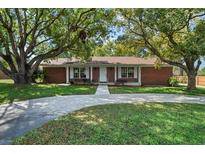 Charming brick home with mature trees, well-manicured lawn, and inviting curb appeal at 1203 Lake Miriam Dr, Lakeland, FL 33813