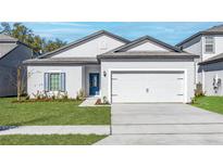 Charming single-Gathering home with a well-maintained lawn, blue door, and two-car garage at 13279 Tula Loop, Astatula, FL 34705