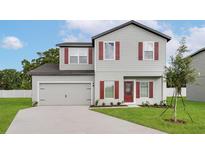 Charming two-story home featuring red window shutters, a gray exterior, and a well-maintained front lawn at 13450 Leaping Water Way, Astatula, FL 34705