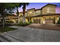 Townhome exterior showing covered garages, tropical landscaping, and multi-tone facade at 8983 Azalea Sands Ln # 8983, Davenport, FL 33896