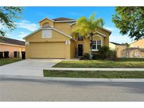 Charming yellow two-story home with a well-manicured lawn and attached two-car garage at 1802 Royal Ridge Dr, Davenport, FL 33896