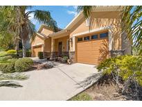 Charming home exterior featuring a three-car garage, stone accents, and mature landscaping at 1892 Sanderling Dr, Clermont, FL 34711